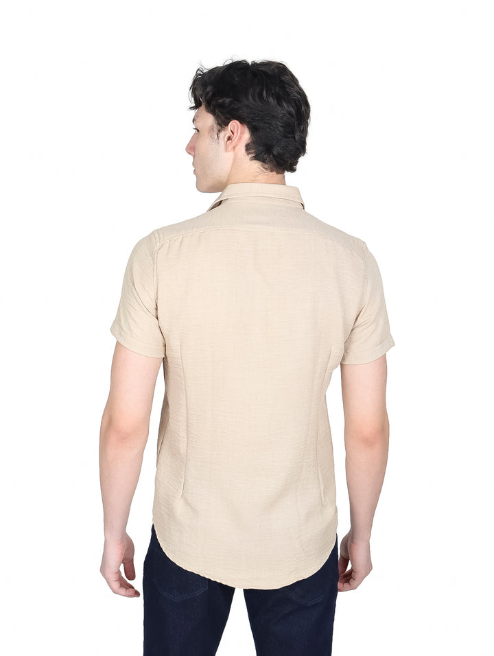 Hombre vistiendo camisa de manga corta color beige con botones y pantalones azul marino.