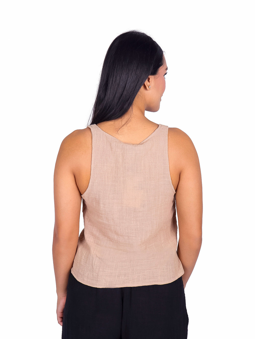 Mujer vistiendo blusa color arena sin mangas con detalle de surcido frontal y pantalones negros.