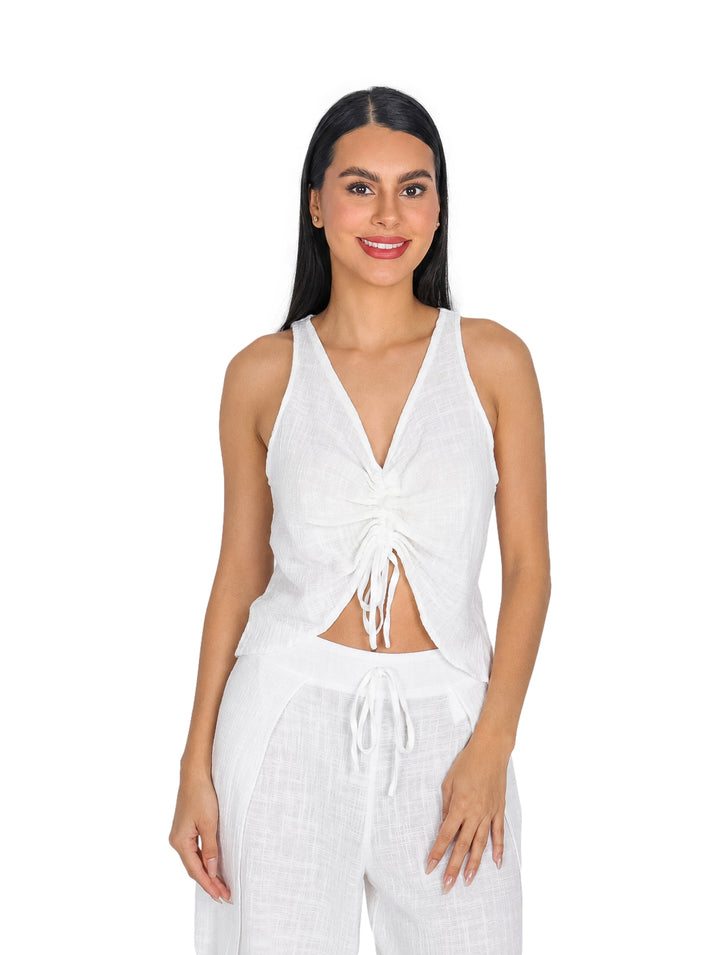 Mujer vistiendo blusa blanca sin mangas con escote en V y detalle de ajuste frontal surcido.