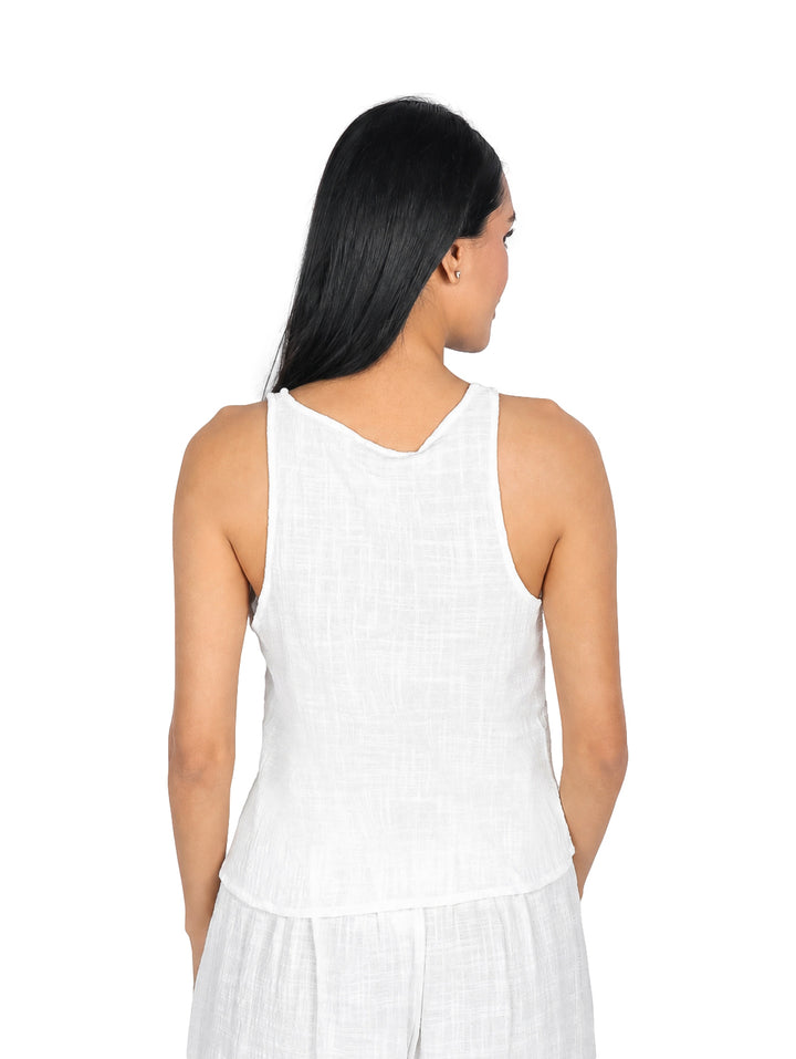 Mujer vistiendo blusa blanca sin mangas con escote en V y detalle de ajuste frontal surcido.