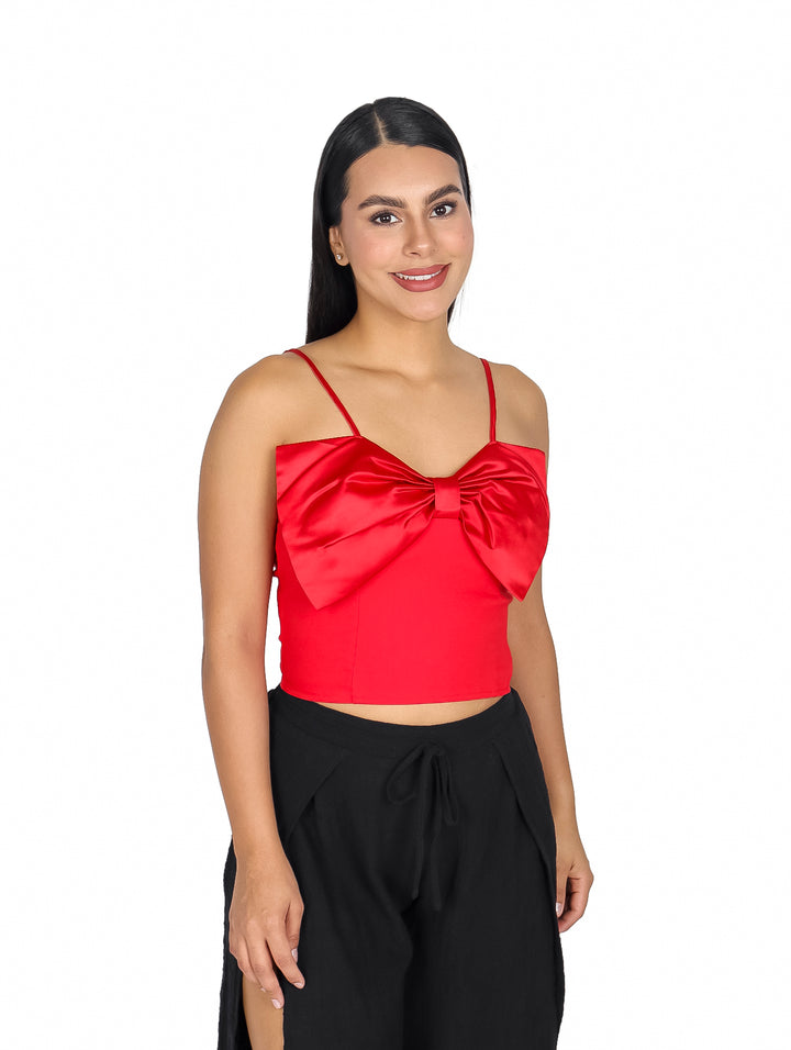 Mujer vistiendo blusa roja de tirantes con un moño grande decorativo en el pecho.