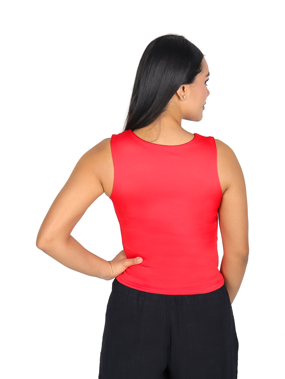 Mujer vistiendo blusa roja sin mangas con escote y pantalones negros.