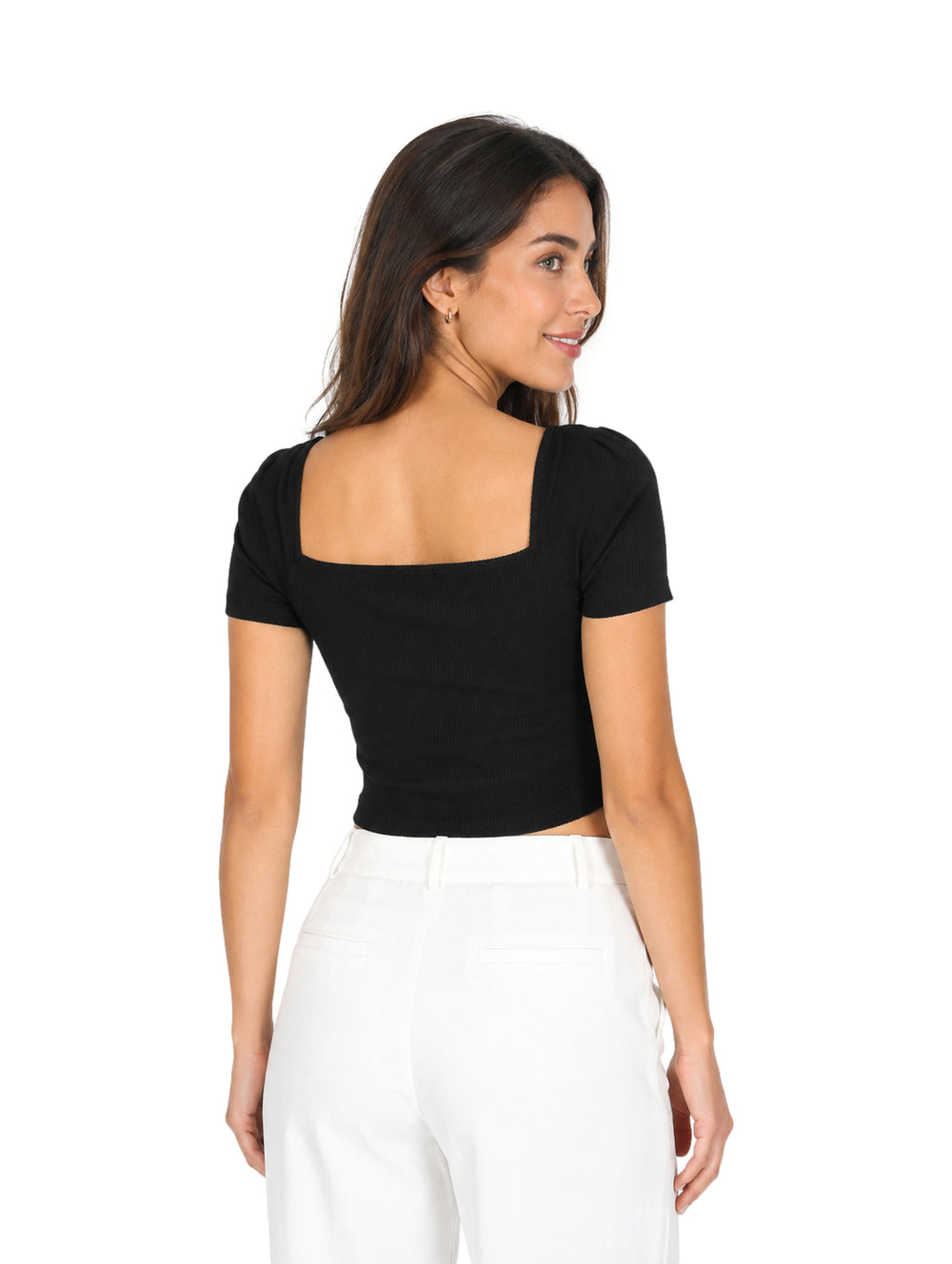 Mujer vistiendo una blusa negra corta de manga corta y cuello cuadrado con pantalones blancos.