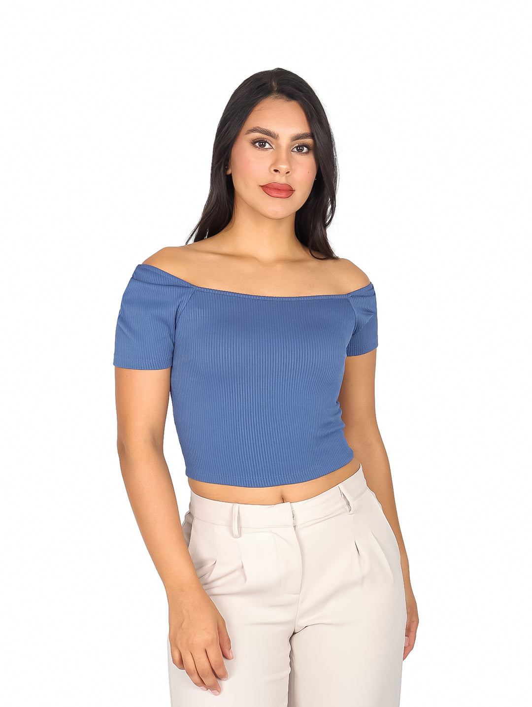 Mujer vistiendo blusa azul a los hombros de textura acanalada y pantalones blancos.