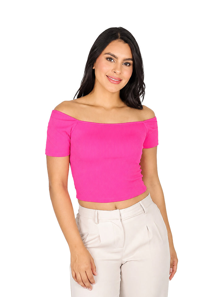 Mujer vistiendo una blusa rosa ajustada de hombros descubiertos y pantalones blancos.