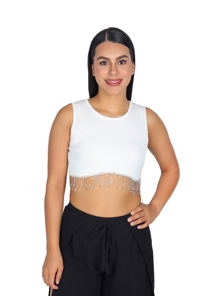 Mujer vistiendo un top corto blanco sin mangas con flecos y cuentas en el borde inferior.