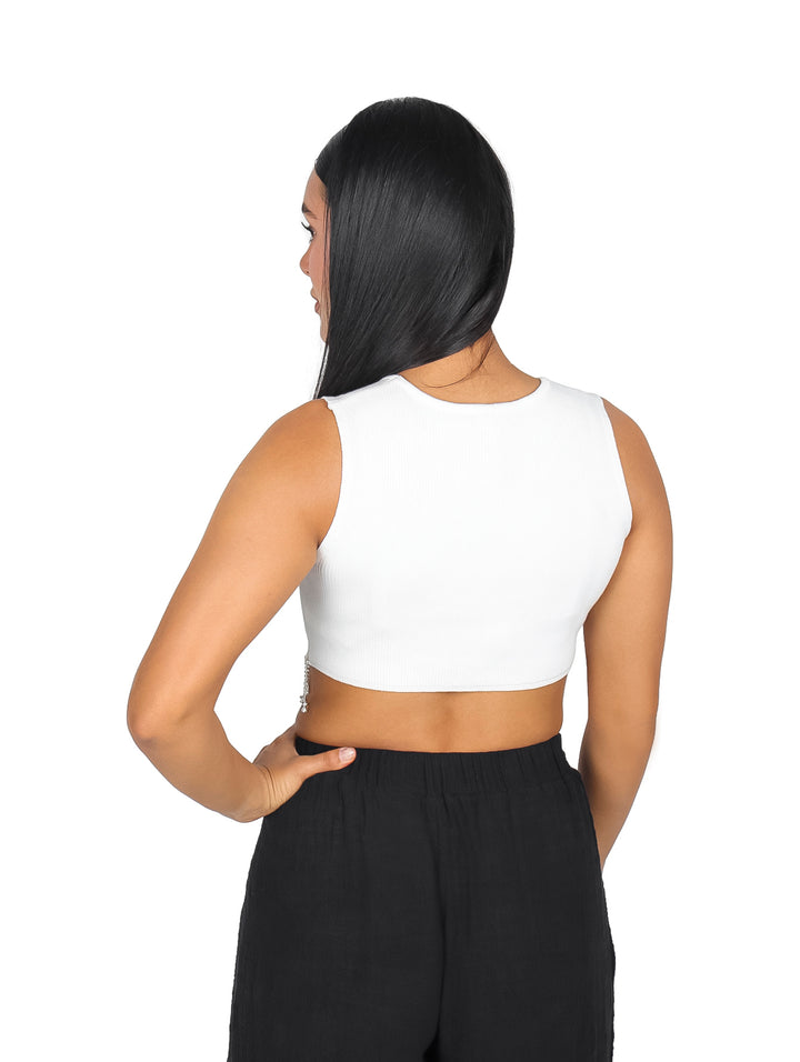 Mujer vistiendo un top corto blanco sin mangas con flecos y cuentas en el borde inferior.