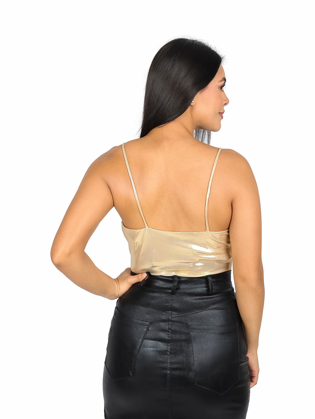 Mujer vistiendo un body dorado metálico de tirantes finos y falda negra.