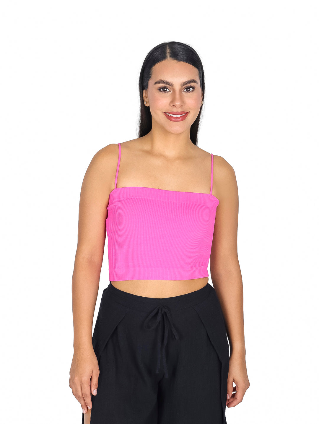 Mujer vistiendo una blusa crop top color fucsia con tirantes y pantalones negros sobre fondo blanco.