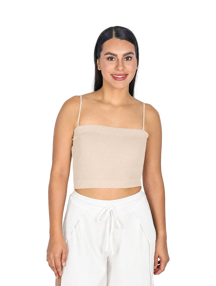 Mujer modelando blusa crop top color camel con tirantes delgados y pantalones blancos.