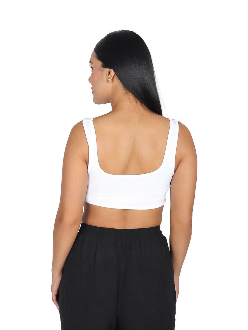Mujer vistiendo un top tipo corset blanco corto y pantalones negros.