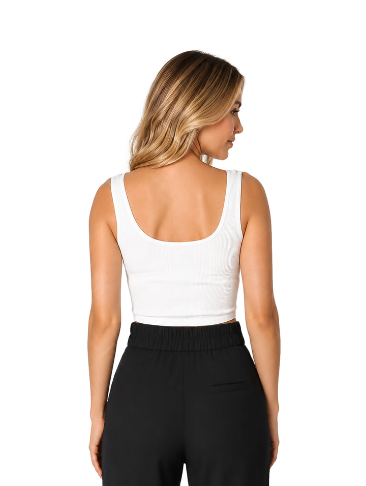 Mujer usando un top básico blanco corto y ajustado con pantalones negros.