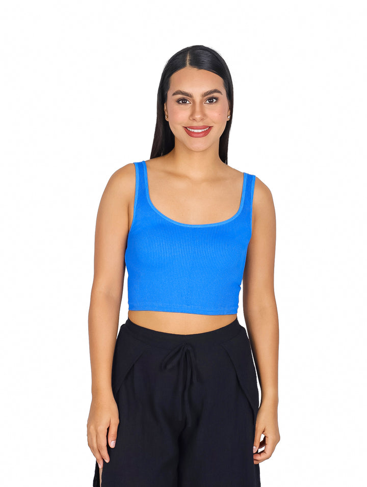 Mujer vistiendo un top básico azul acanalado sin mangas y pantalones negros.