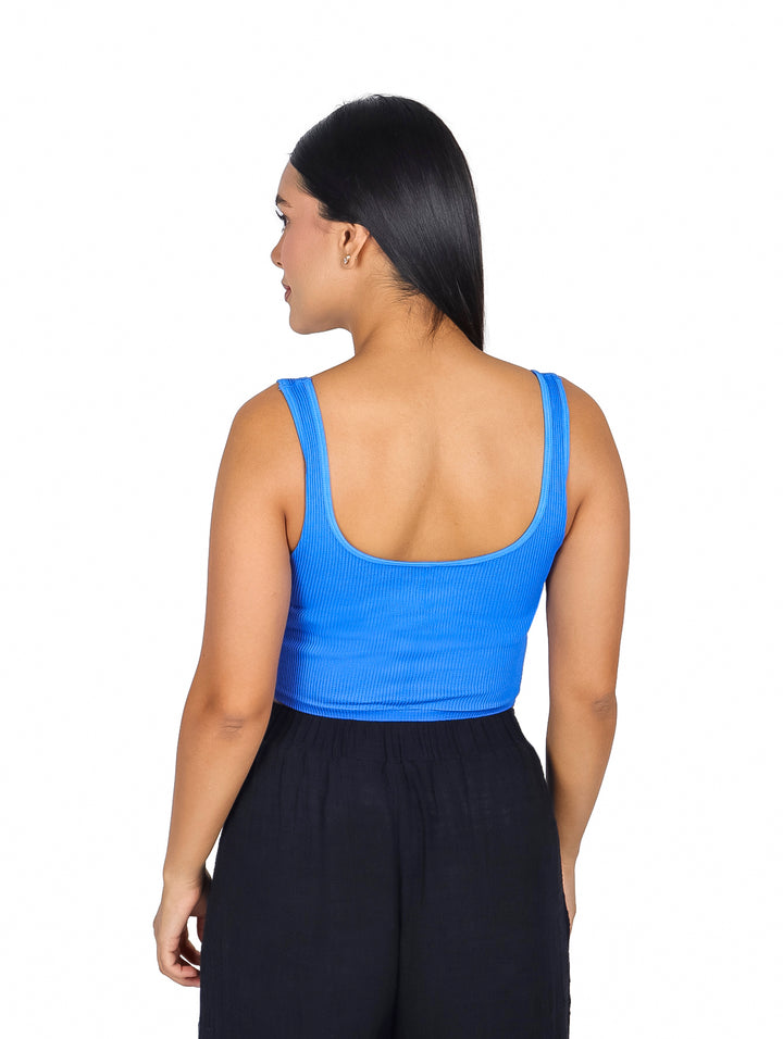 Mujer vistiendo un top básico azul acanalado sin mangas y pantalones negros.