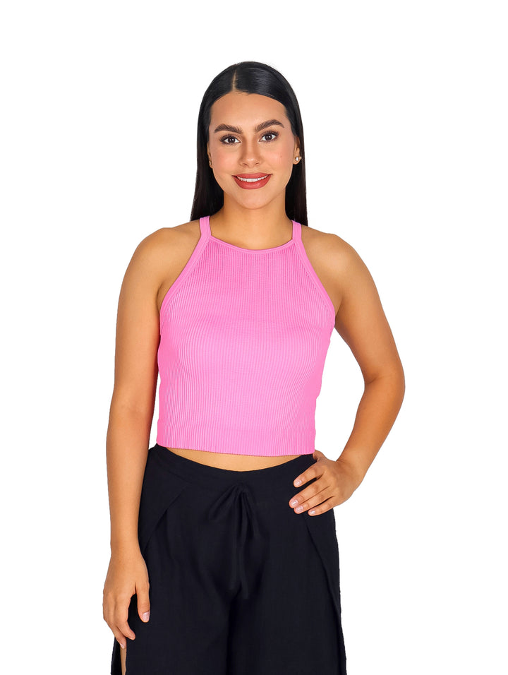 Mujer vistiendo una blusa rosa sin mangas de cuello halter y pantalones negros.