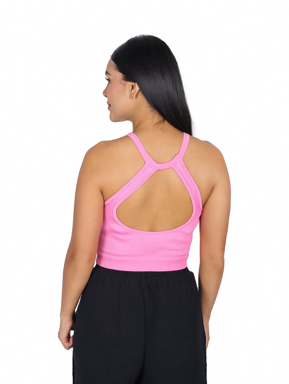 Mujer vistiendo una blusa rosa sin mangas de cuello halter y pantalones negros.