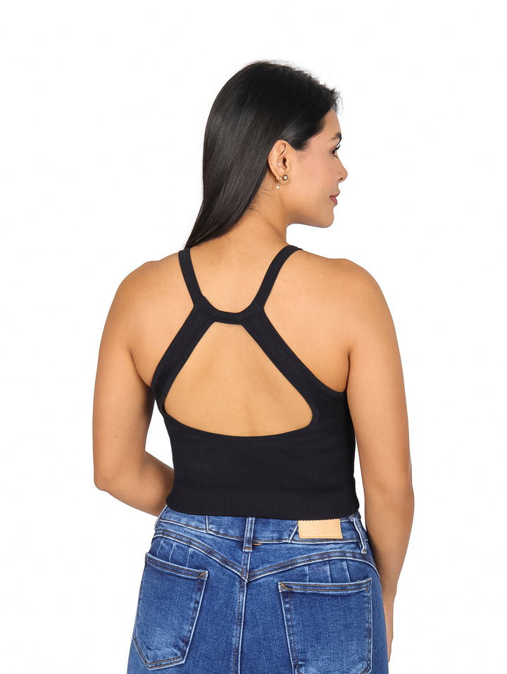 Mujer vistiendo blusa negra sin mangas de cuello halter y pantalones vaqueros azules.