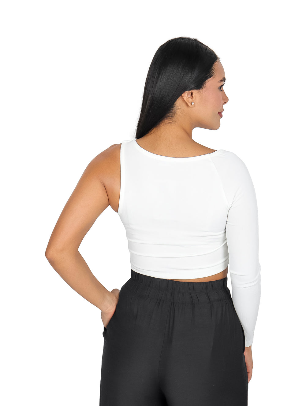 Mujer vistiendo una blusa blanca corta de una sola manga y pantalones negros sobre fondo blanco.