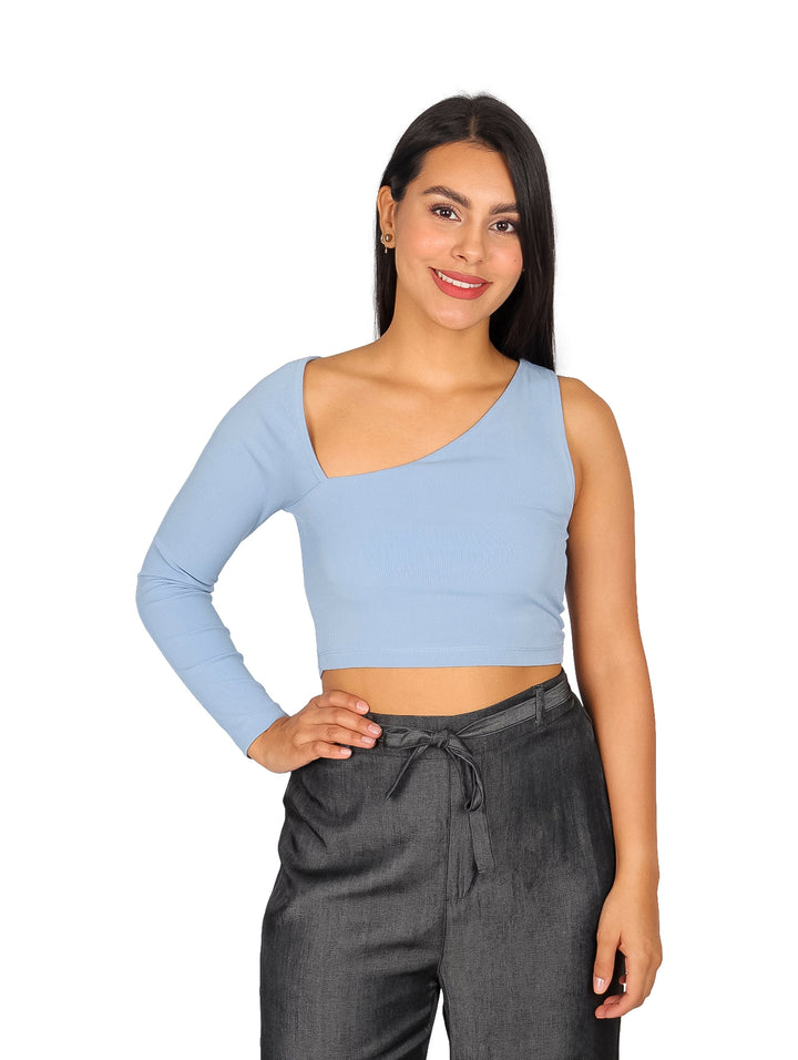 Mujer vistiendo blusa azul claro asimétrica de una sola manga y pantalones grises.