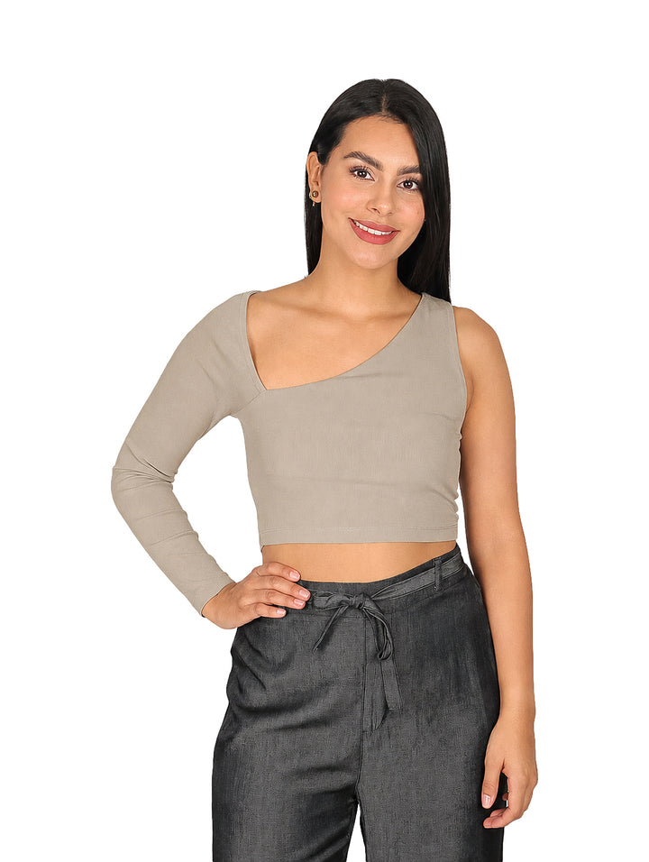 Mujer vistiendo blusa asimétrica de una sola manga en color camel y pantalones grises.