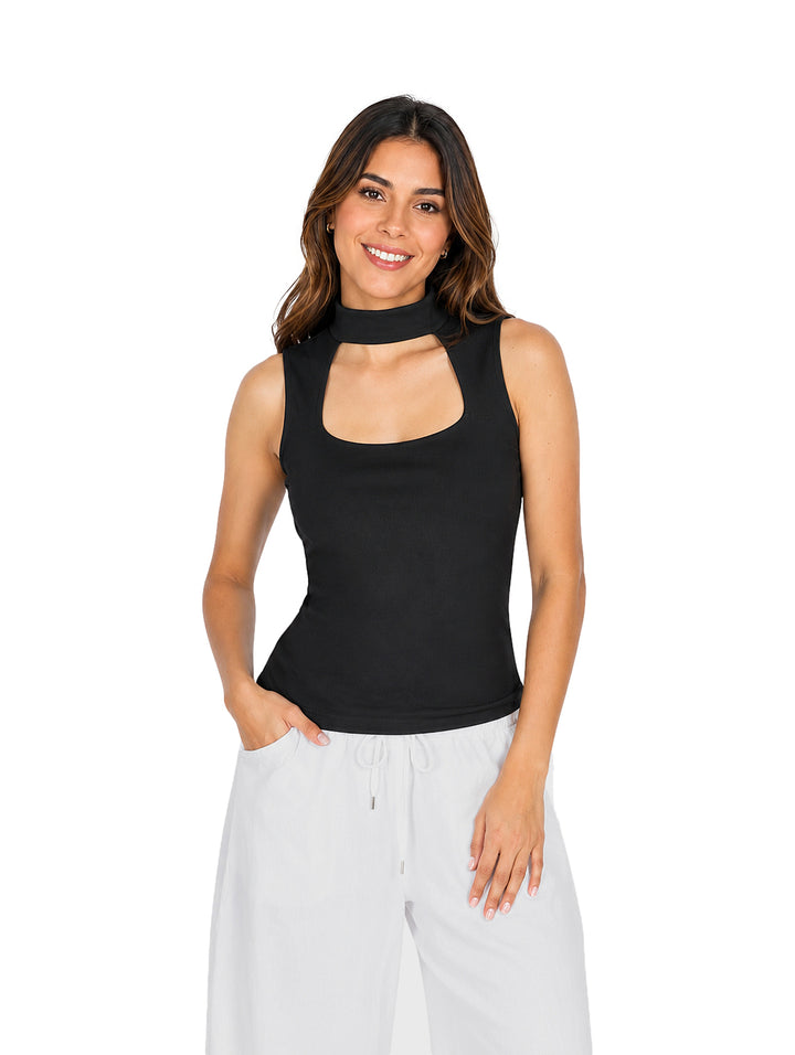 Mujer vistiendo blusa negra sin mangas con abertura en el cuello y pantalones blancos.