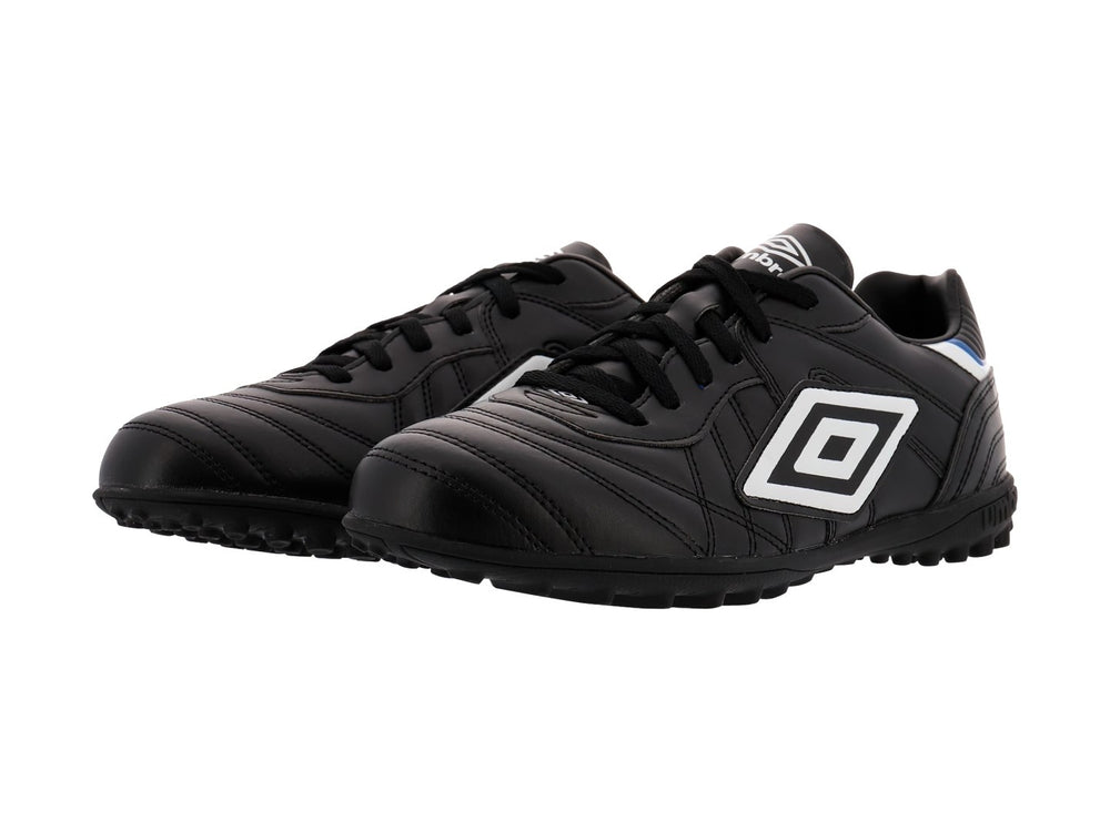 Zapato de fútbol Umbro color negro con detalles en blanco y azul y suela para césped sintético.
