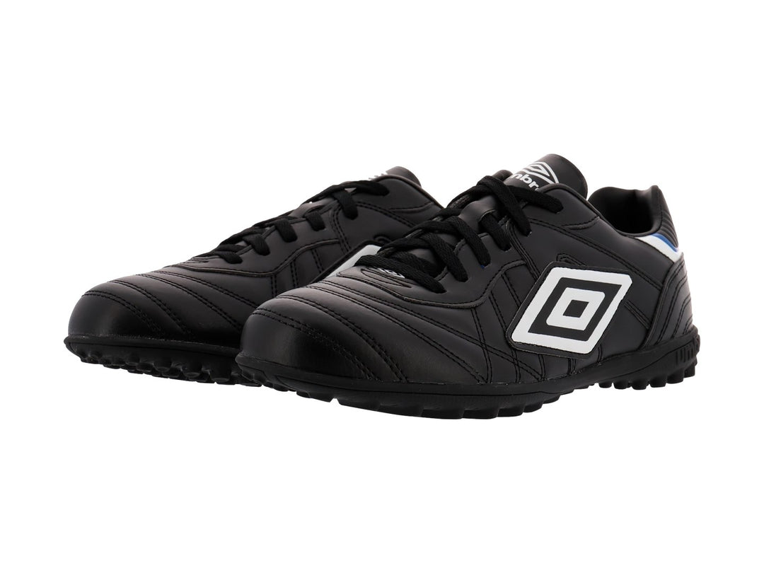 Zapato de fútbol Umbro color negro con detalles en blanco y azul y suela para césped sintético.