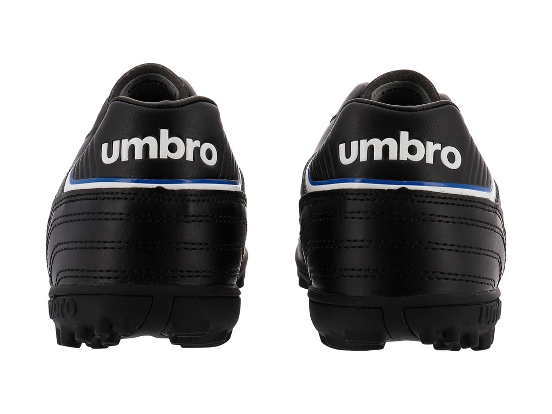 Zapato de fútbol Umbro color negro con detalles en blanco y azul y suela para césped sintético.
