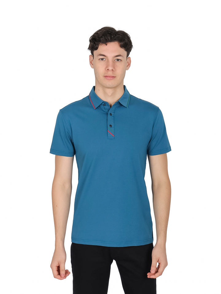 Hombre vistiendo una playera polo color teal con detalles en rojo y verde en el cuello y pechera.