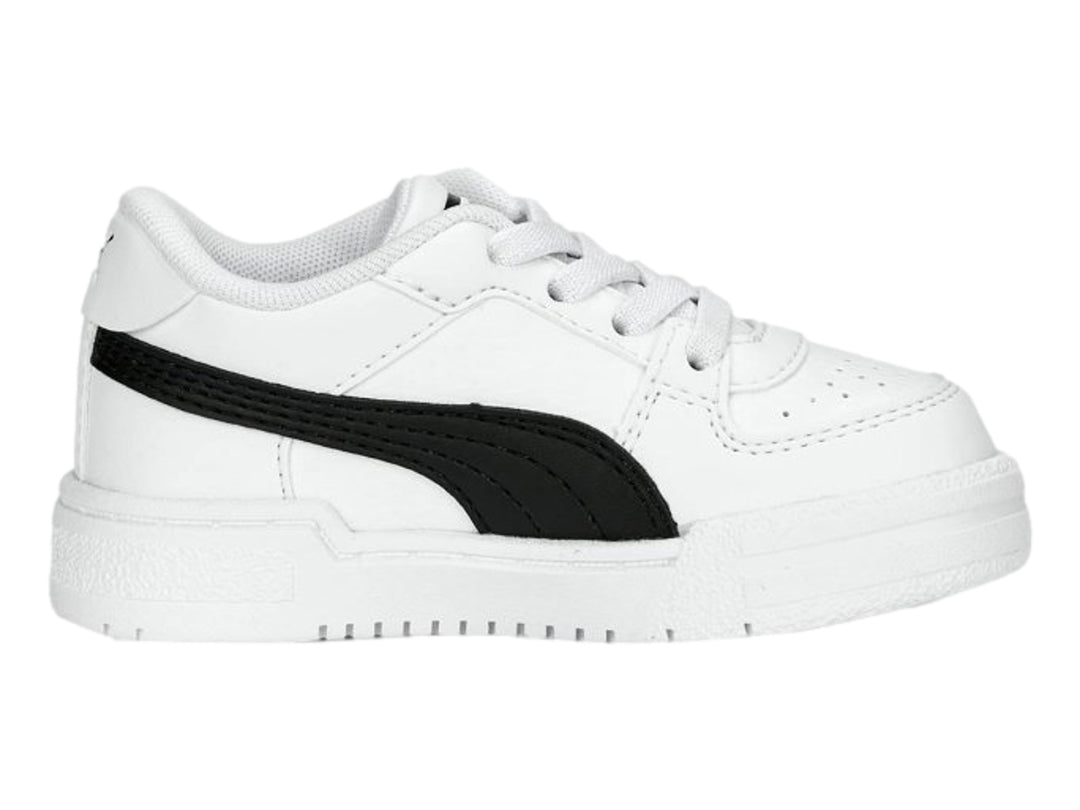 Tenis PUMA blancos con franja negra lateral y suela blanca para niños.