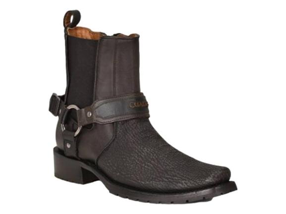 Bota negra de piel de tiburón con correa y detalle de anillo metálico en el tobillo.
