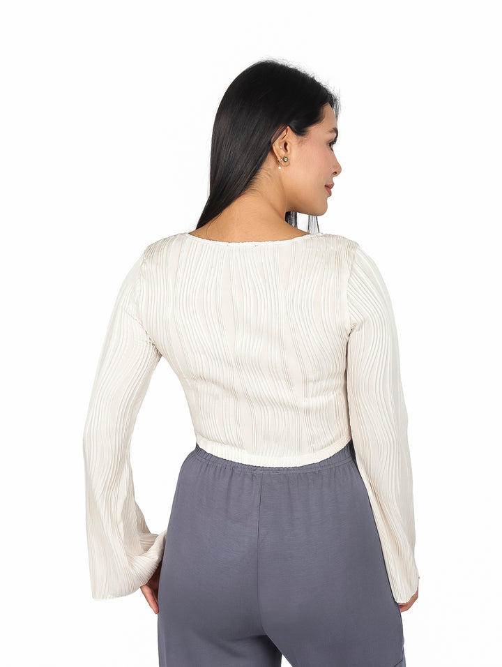 Mujer vistiendo blusa beige de cuello cuadrado y mangas campana con textura acanalada.