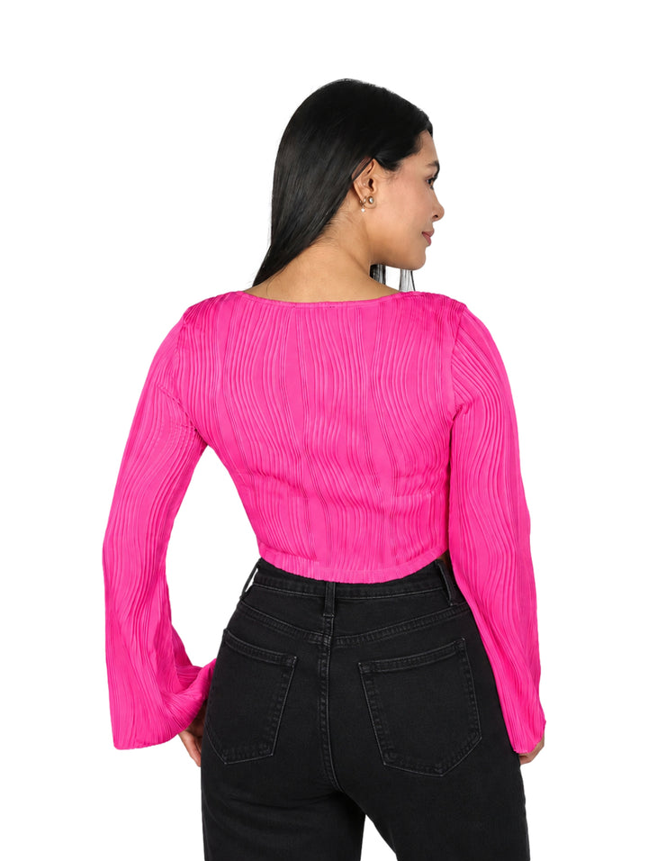 Mujer vistiendo blusa rosa corta con mangas campana y textura acanalada.