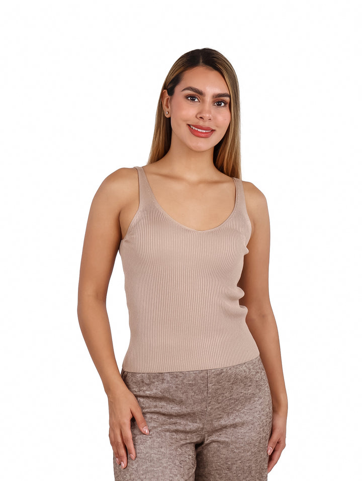 Mujer vistiendo una blusa sin mangas color beige con textura acanalada.