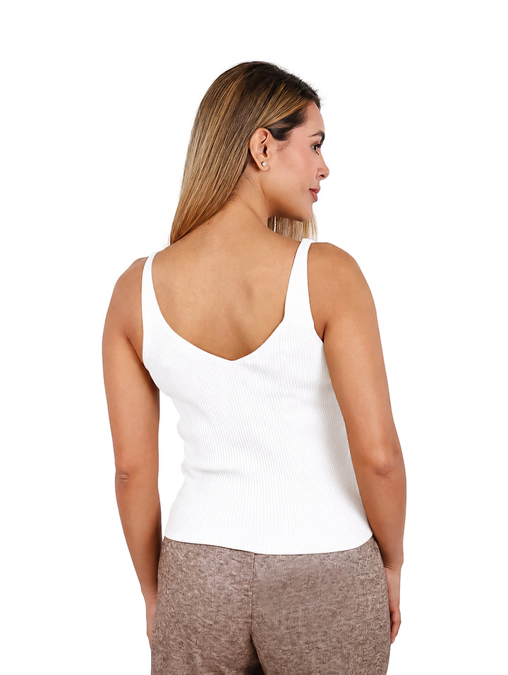 Mujer vistiendo una blusa blanca sin mangas de cuello redondo y textura acanalada.