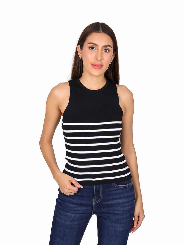 Mujer vistiendo blusa sin mangas a rayas horizontales negras y blancas con pantalones jeans azules.