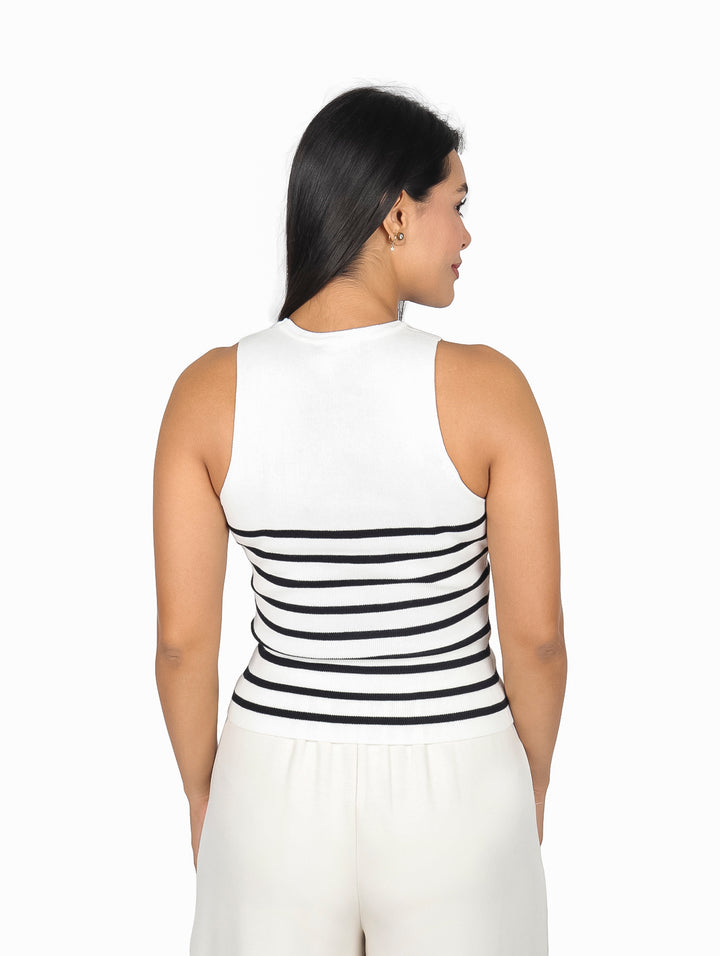 Mujer vistiendo blusa blanca sin mangas con rayas horizontales negras.