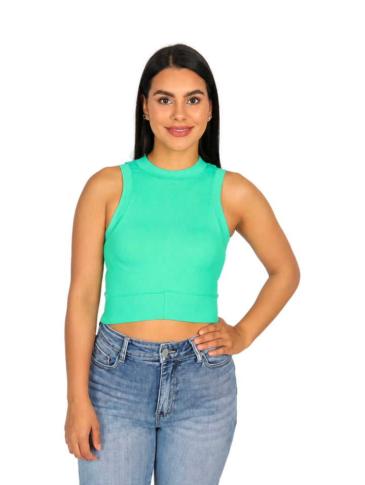 Mujer usando un top verde sin mangas y jeans azules sobre fondo blanco.