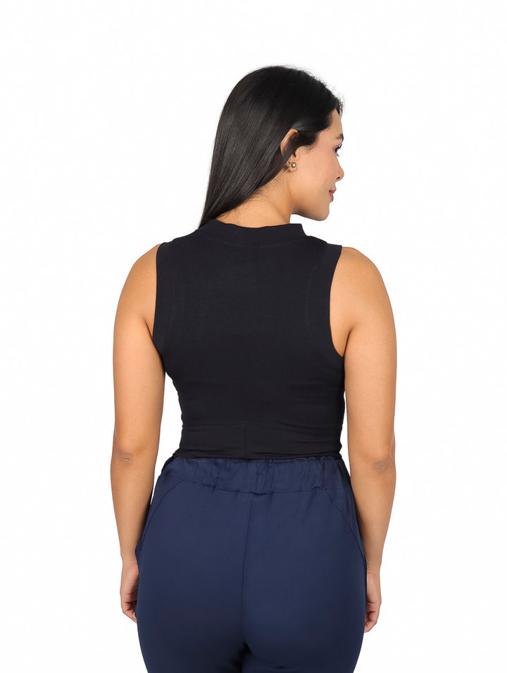 Mujer vistiendo un top negro sin mangas de cuello redondo y pantalones azul marino.