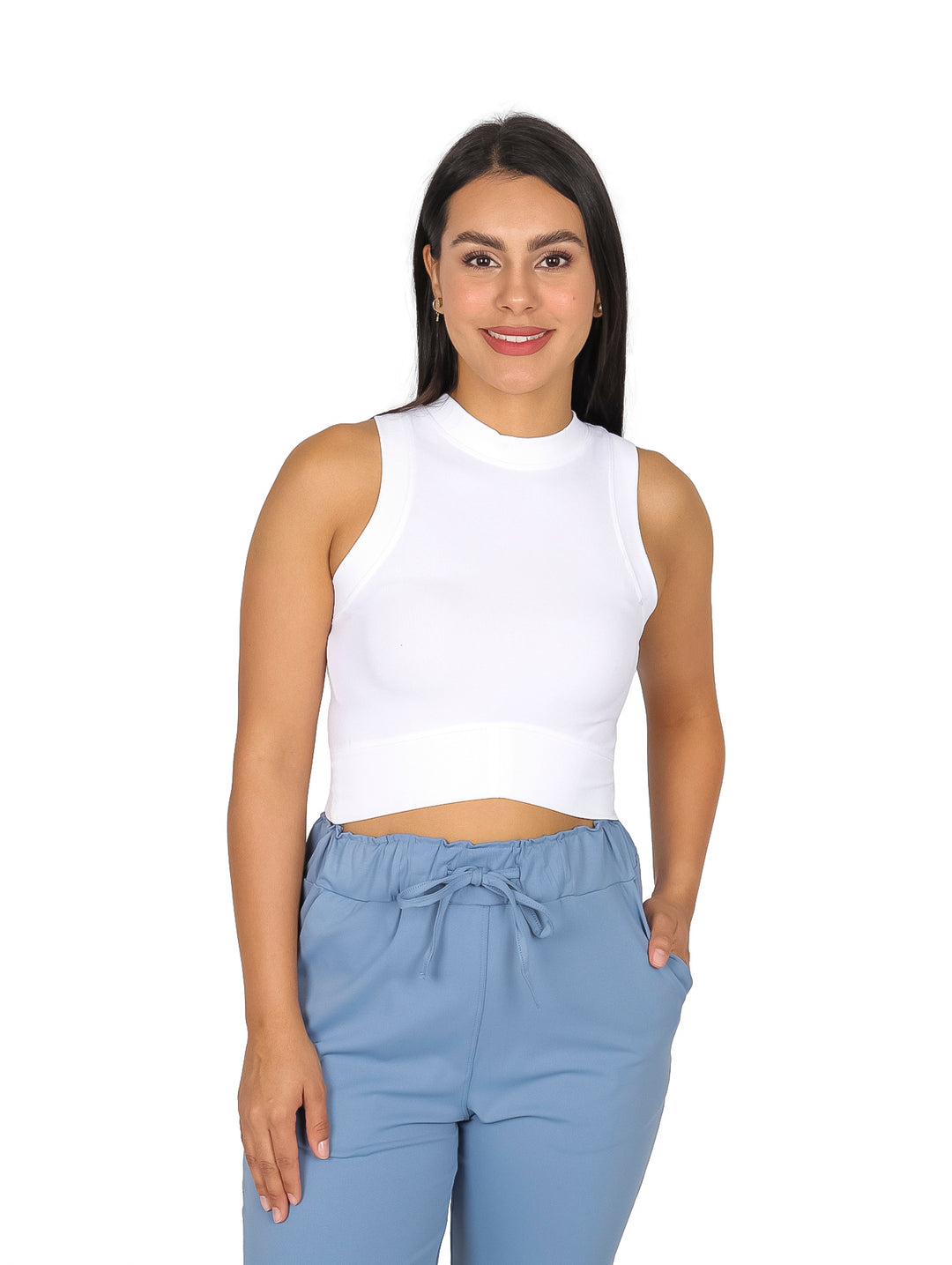 Mujer vistiendo un top blanco sin mangas y pantalones azul claro sobre fondo blanco.