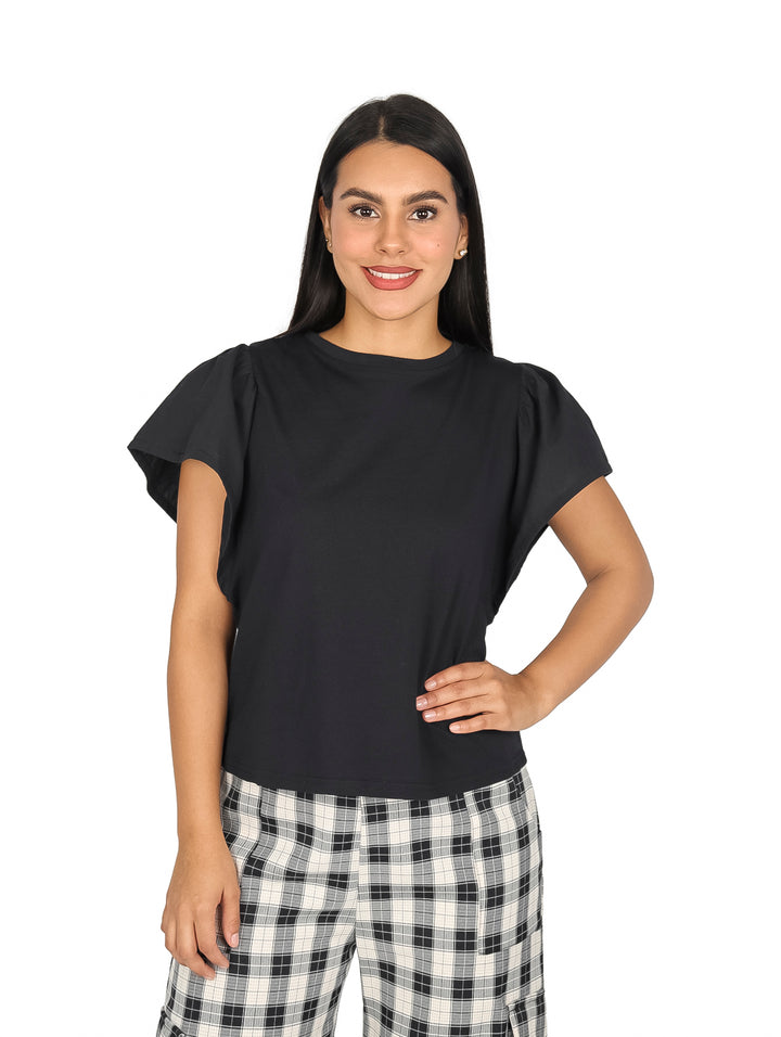 Mujer vistiendo una blusa negra de manga corta con detalle de escarlola y pantalones a cuadros.