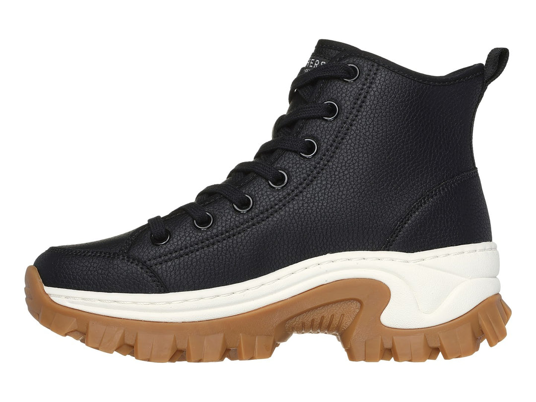 Botín Skechers negro de caña media con suela gruesa color café y detalle blanco en la entresuela.