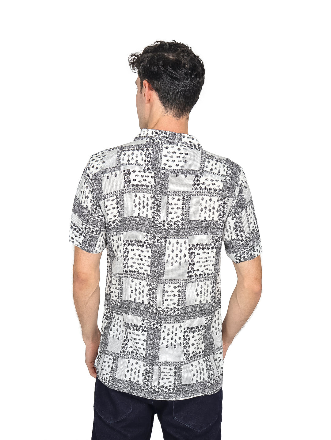 Hombre vistiendo camisa de manga corta color blanco con estampado geométrico en negro, estilo resort.