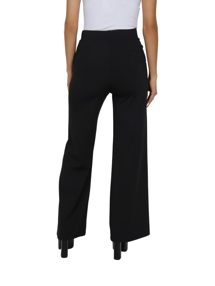Mujer vistiendo un pantalón negro de pierna ancha y talle alto con zapatos de plataforma negros.