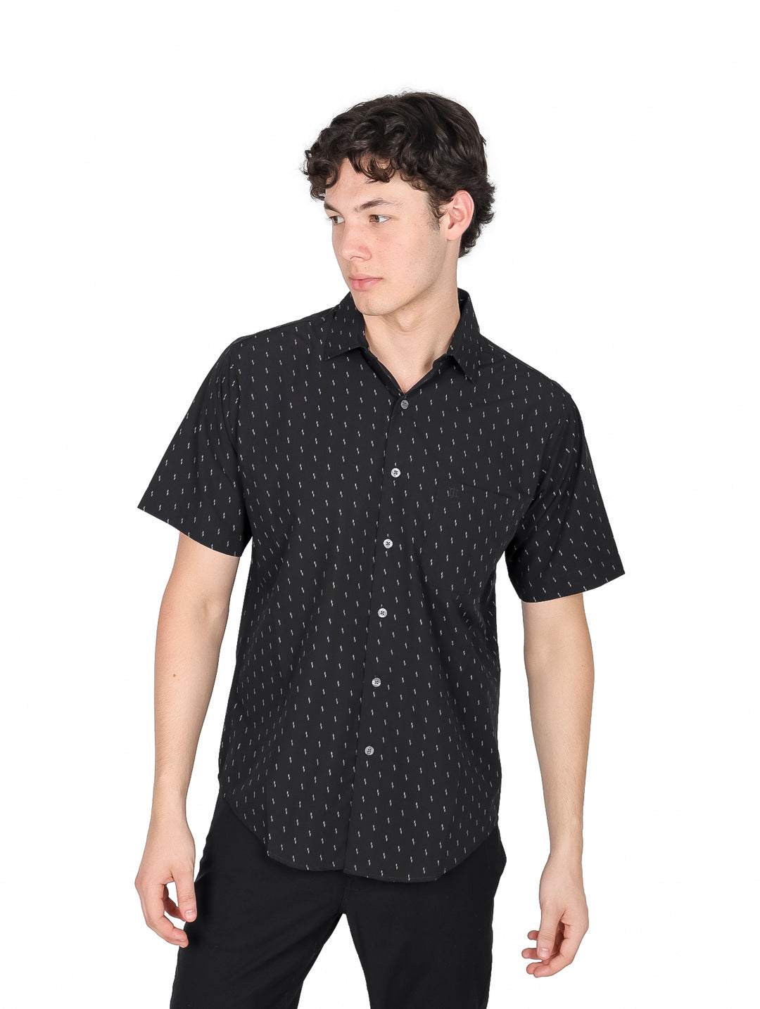 Hombre vistiendo camisa negra de manga corta con estampado de pequeños puntos blancos y cuello.