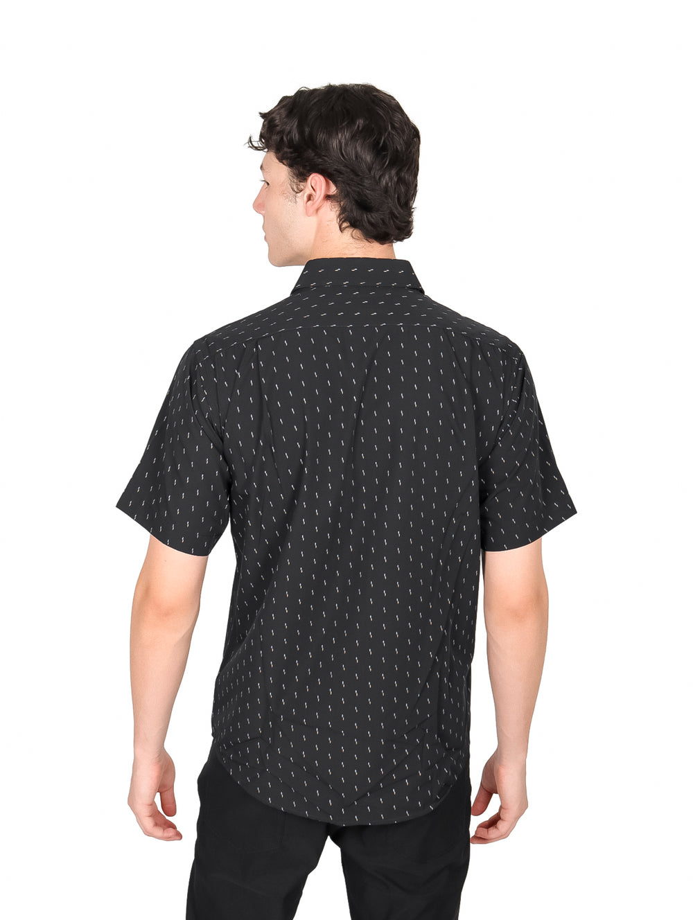 Hombre vistiendo camisa negra de manga corta con estampado de pequeños puntos blancos y cuello.