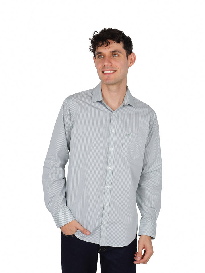 Hombre usando camisa de manga larga color verde mariscal con rayas finas y pantalones oscuros.