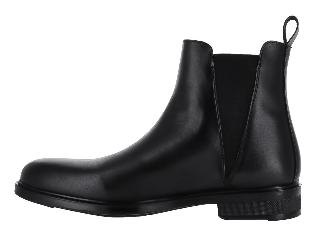 Bota tipo Chelsea de color negro con acabado brillante y elástico lateral.