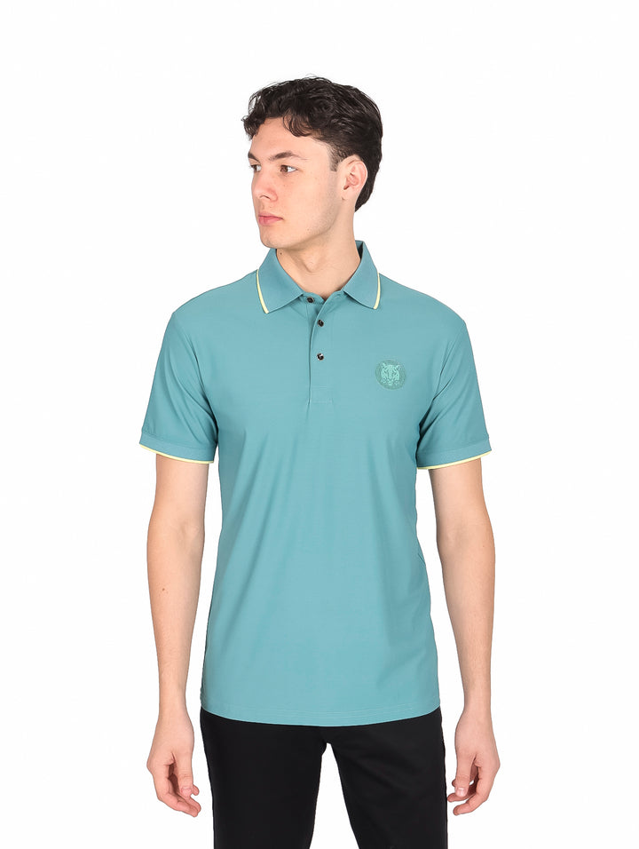 Hombre vistiendo playera polo color teal con detalles amarillos en cuello y mangas.