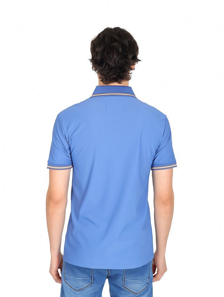 Hombre vistiendo playera polo azul de manga corta con cierre frontal y detalles blancos en cuello y mangas.